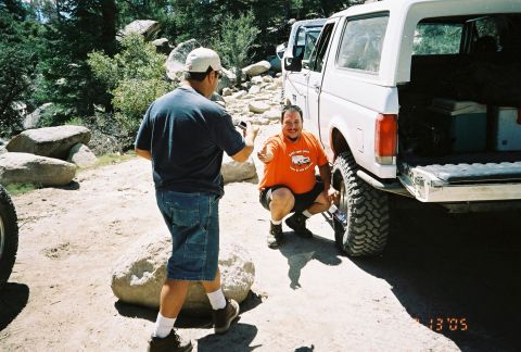 1990 Ford Bronco - Trail scene dated 6-13-05: two men beside a lifted white Ford Bronco with its tailgate down and rear hatch glass up, one crouching by the m…