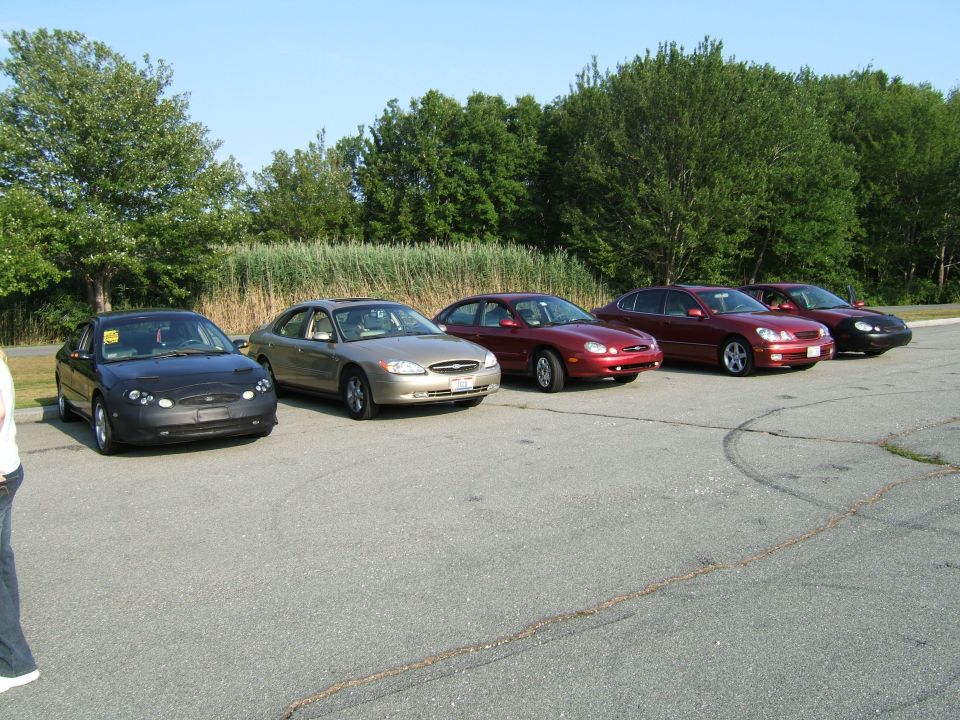 Five sedans parked in a lot, including a black 1998 Ford Taurus and a gold 1998 Ford Taurus