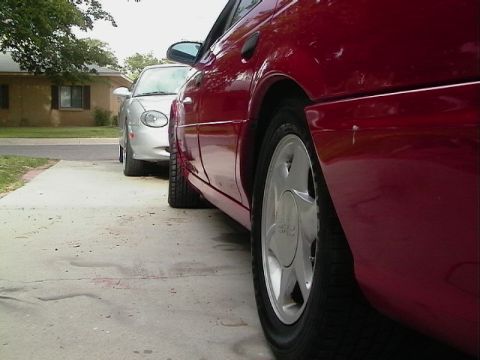 1992 Ford Taurus - Side view of a red car parked on a driveway, with a silver car visible behind it.