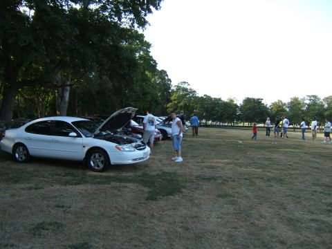 1998 Ford Taurus - White 1998 Ford Taurus with hood open at an outdoor gathering.
