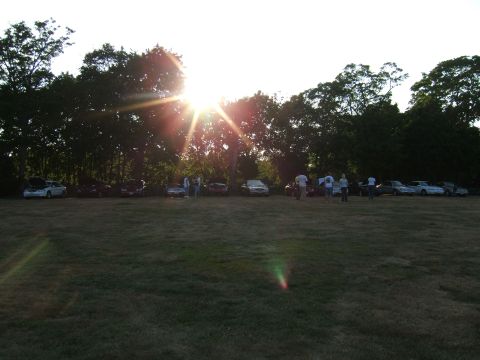 1998 Ford Taurus - Cars and people gathered in a field at sunset.