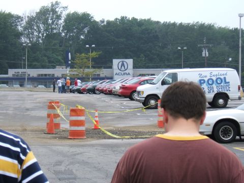 1998 Ford Taurus - A group of cars are parked in a lot, with an Acura dealership and a service van visible in the background.