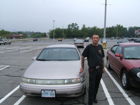 1998 Ford Taurus - A man stands next to a silver 1996 Mercury Sable in a parking lot.