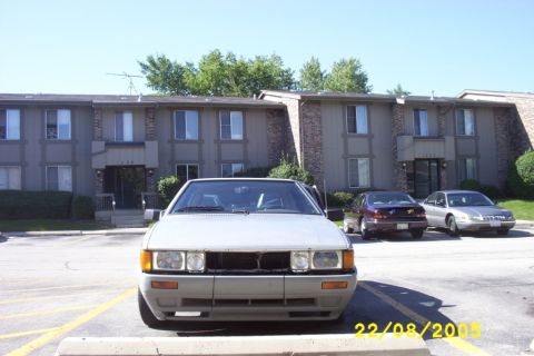 1983 Volkswagen Scirocco - A silver sedan is parked in front of an apartment building, with two other cars visible behind it.