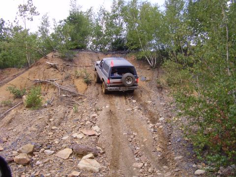 1995 Ford Bronco - Ford Bronco navigates an off-road trail on a steep, rocky incline.