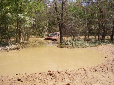 1995 Ford Bronco - Off-road vehicle stuck in a muddy water hole during an outdoor excursion.