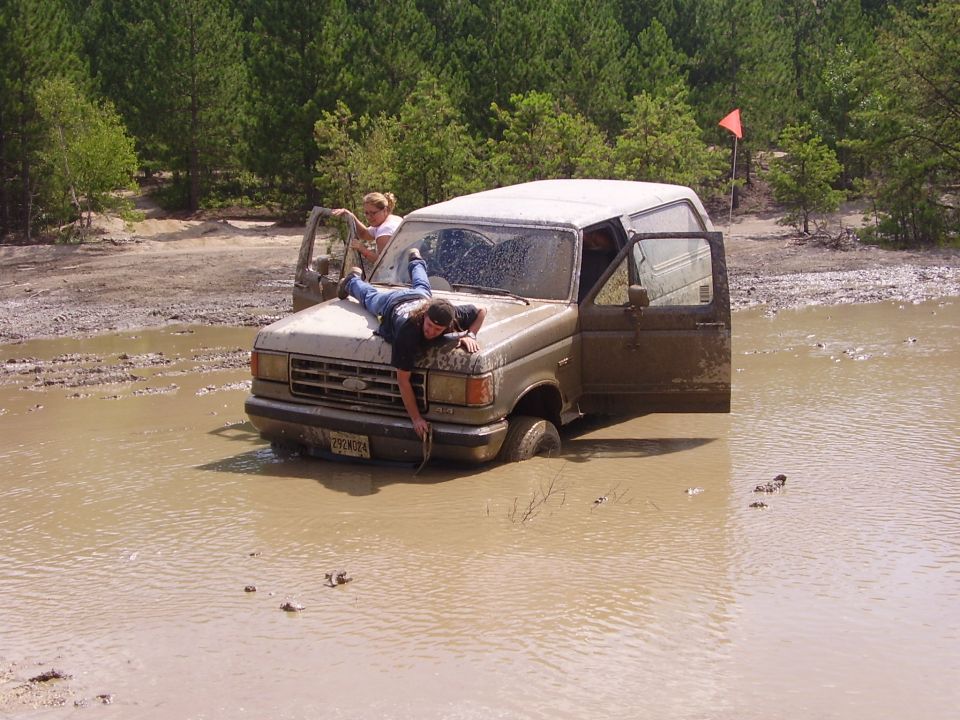 Ford Bronco stuck in mud with two people on it