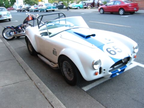 1991 Ford Explorer - A white convertible with blue racing stripes and the number 65 is parked on the street next to a motorcycle.