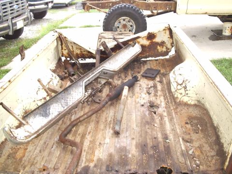 1979 Ford F-150 - A disassembled truck bed contains various rusty parts, with another vehicle visible in the background.
