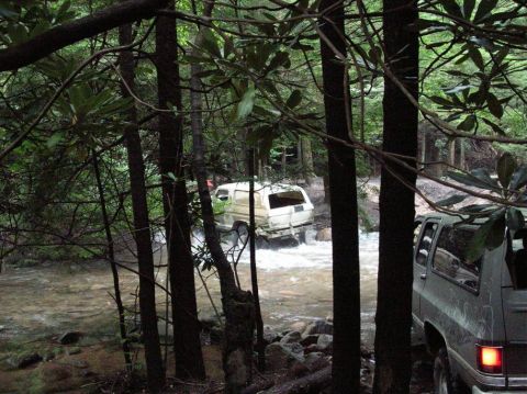 1995 Ford Bronco - Two SUVs are parked near a stream, while a white van drives through the water.