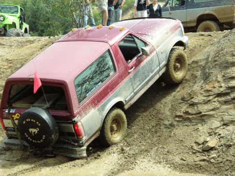 1995 Ford Bronco - A Ford Bronco navigates a challenging off-road course with other vehicles and spectators present.