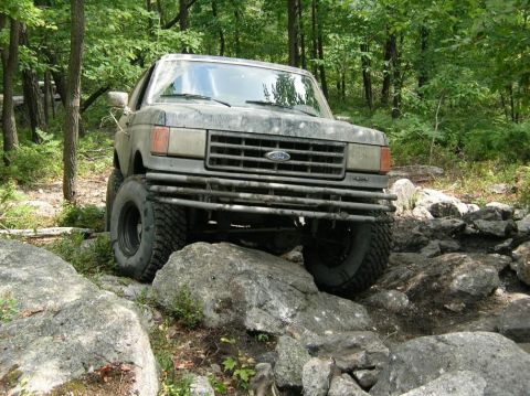 1995 Ford Bronco - This Ford Bronco is tackling a challenging rocky terrain in a wooded area.