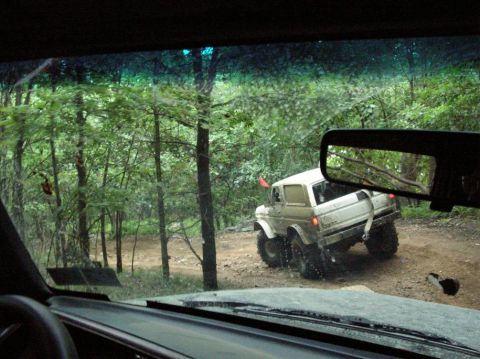 1995 Ford Bronco - View from inside a vehicle looking out at another off-road vehicle on a dirt path.