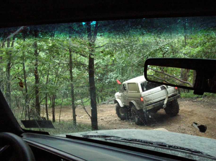 Off-road vehicle driving on dirt road through trees