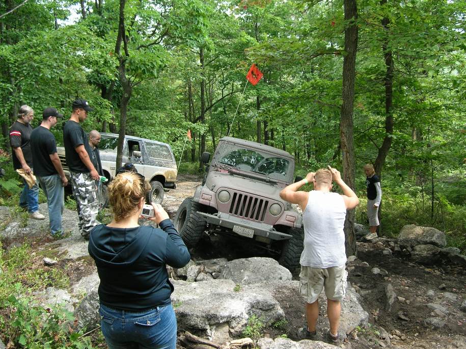 Off-road vehicle navigating rocks with people watching