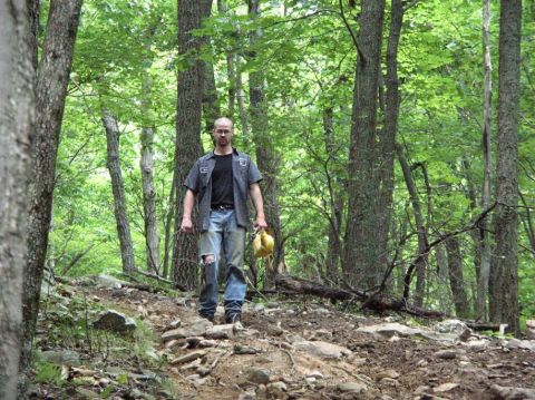 1995 Ford Bronco - A man stands on a rocky path in a wooded area, holding a yellow object.