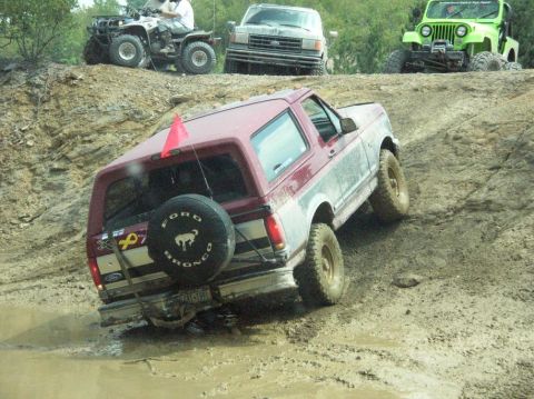 1995 Ford Bronco - A Ford Bronco navigates a challenging off-road course, with other vehicles in the background.