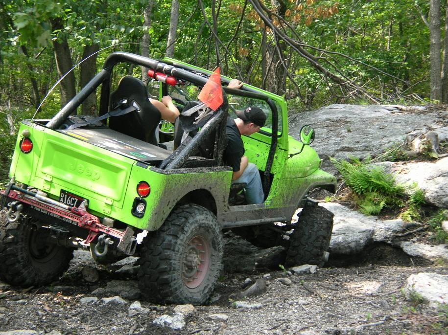 Green Jeep on rocky trail, driver visible