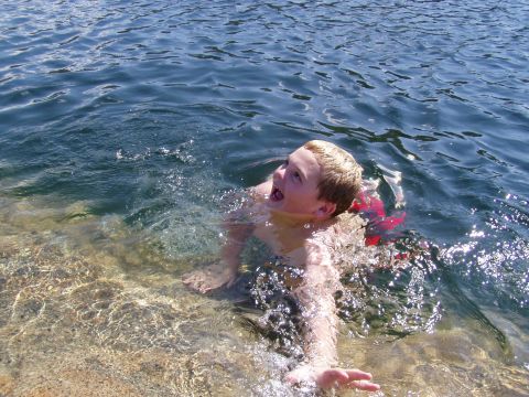 1967 Ford Bronco - A young boy enjoys a swim in the clear, shallow water of a lake.