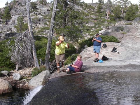 1967 Ford Bronco - Three people enjoy fishing by a waterfall in a rocky, wooded area.