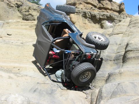 1982 Ford Customline - An off-road vehicle has rolled onto its side while navigating a steep, rocky landscape.
