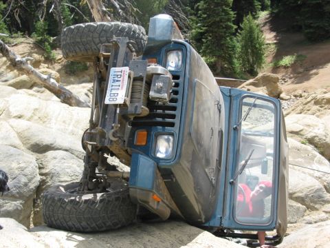 1982 Ford Customline - Off-road vehicle has flipped onto its side while navigating difficult terrain.