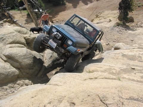 1982 Ford Customline - A teal Jeep Wrangler tackles a challenging rocky trail, demonstrating its off-road capabilities.