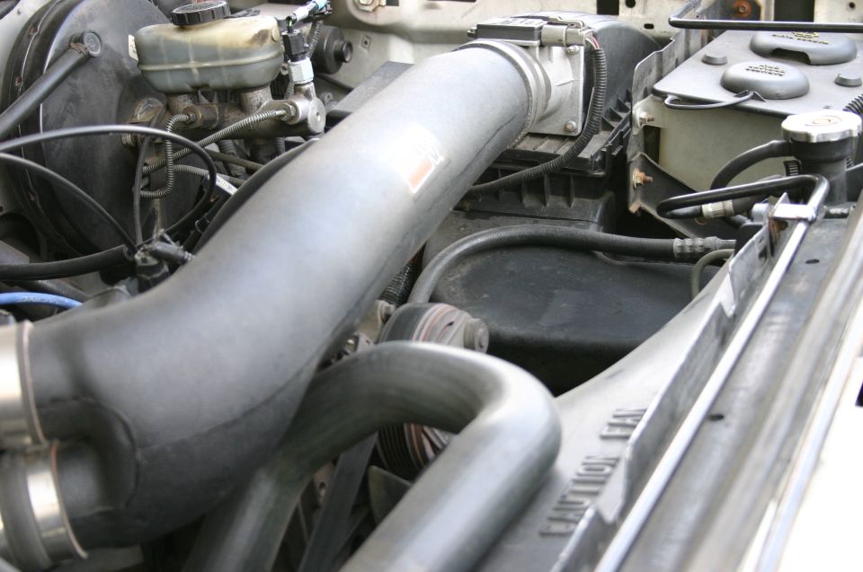 Engine bay with large gray and black intake piping and brake reservoir