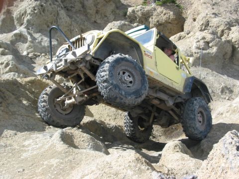 1982 Ford Customline - This modified jeep is navigating a steep, rocky incline off-road.