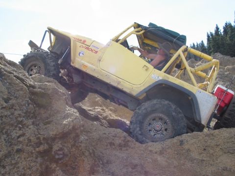 1982 Ford Customline - This modified jeep navigates a challenging rocky incline, its off-road capabilities.
