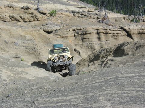 1982 Ford Customline - Jeep CJ-5 navigates a challenging off-road terrain with steep, layered rock formations.