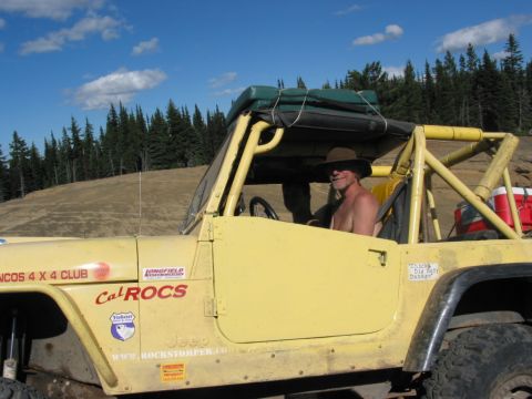 1982 Ford Customline - A yellow Jeep, likely modified for off-roading, is seen with a driver and various club decals on its exterior.