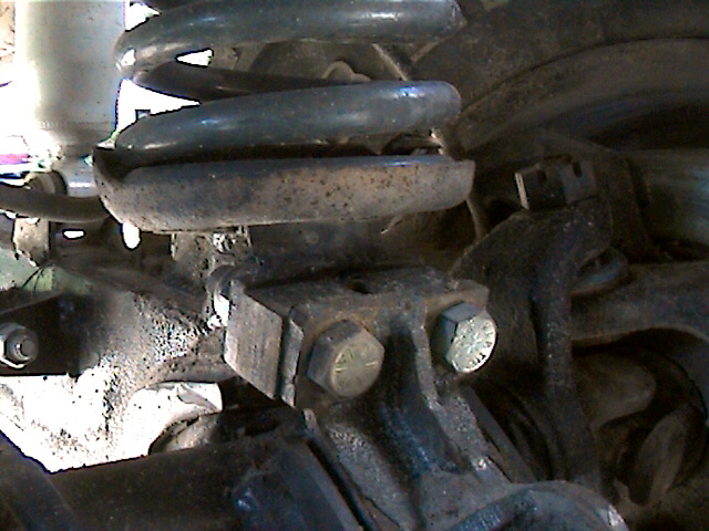 Close-up of a rusty truck suspension component with a coil spring