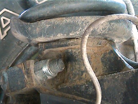 1977 Ford F-150 - This image shows a close-up view of a truck's suspension system, focusing on a rusty metal component and a threaded bolt. The Supermotors.n…