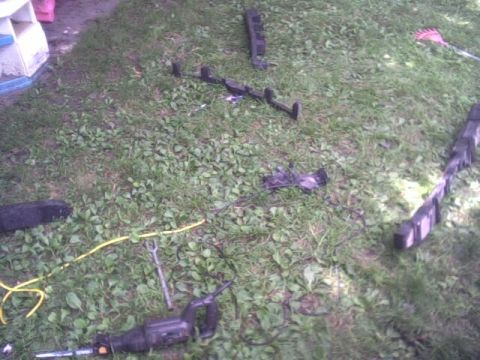 2005 Chevrolet Cavalier - Body panels and tools are scattered on a grassy area, suggesting a repair or dismantling project.