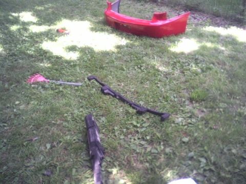 2005 Chevrolet Cavalier - A red car bumper and various yard tools are lying on the grass.