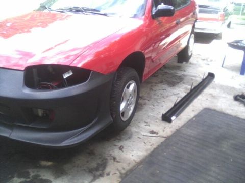 2005 Chevrolet Cavalier - The front of a red car is shown with its bumper removed and one headlight missing.