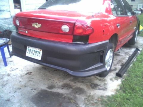 2005 Chevrolet Cavalier - The rear of a red sedan is shown, a black aftermarket bumper and a license plate.