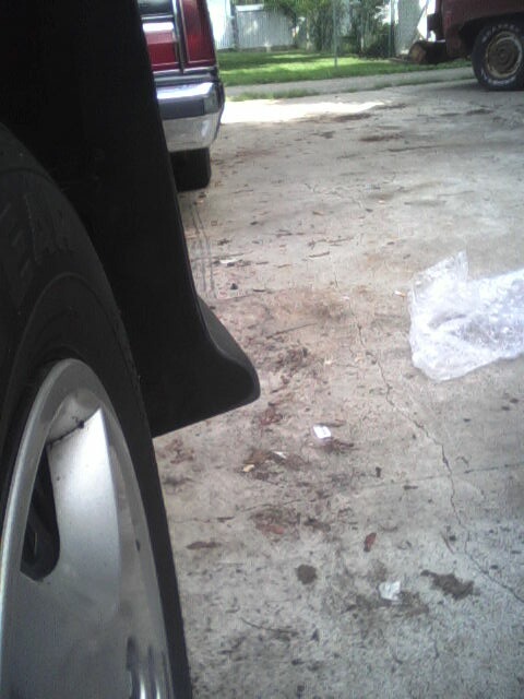 2005 Chevrolet Cavalier - A close-up view of a car's fender and wheel, with other vehicles visible in the distance.