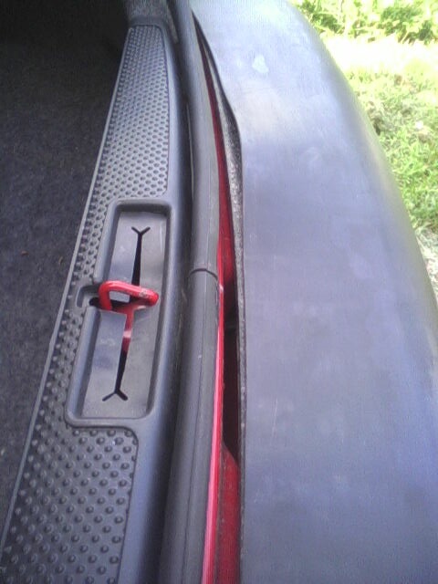 2005 Chevrolet Cavalier - Interior view of a car's door latch mechanism, showing the red pull tab.