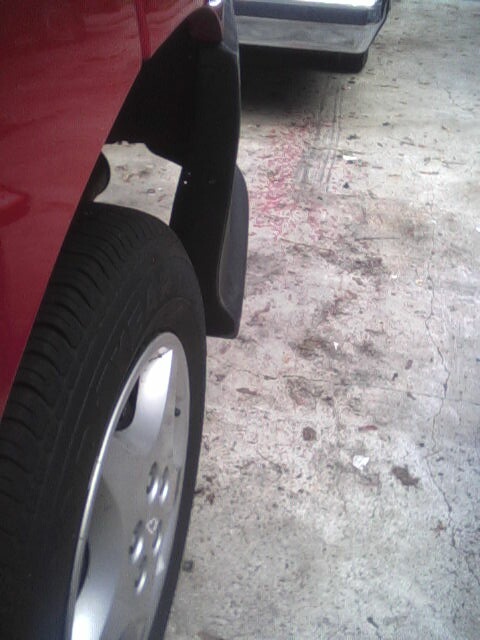 2005 Chevrolet Cavalier - A red vehicle's wheel and fender are shown, with another vehicle visible in the background.