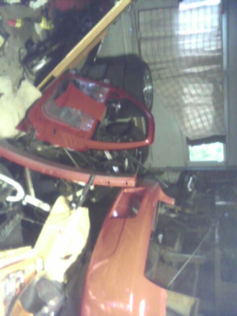 2005 Chevrolet Cavalier - Disassembled red car parts are stored in a garage with various tools and equipment.