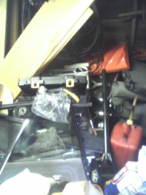 2005 Chevrolet Cavalier - A disorganized garage scene contains various items, including a red gas can and wooden boards.