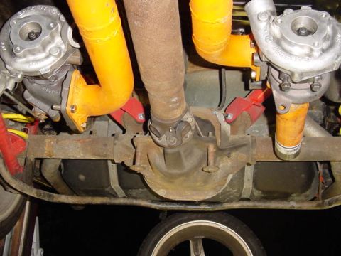1995 Ford Mustang - Close-up view of the undercarriage showing twin turbochargers and bright orange exhaust piping.