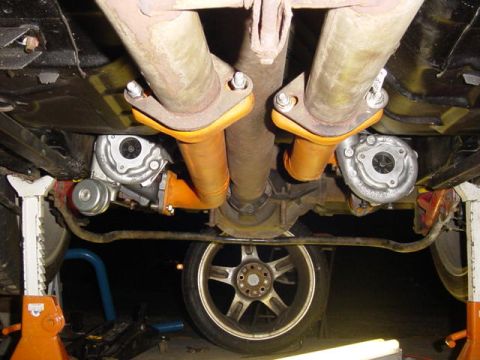 1995 Ford Mustang - The underside of a vehicle is visible, supported by orange jack stands, with a focus on the exhaust system and turbochargers.