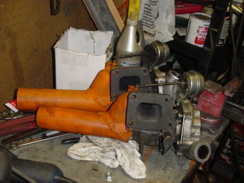 1995 Ford Mustang - Twin turbochargers and orange exhaust manifolds are shown on a cluttered workbench, possibly for a performance vehicle.