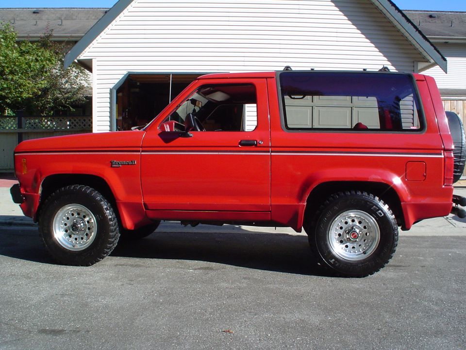 Red 1988 Ford Bronco II parked in front of a garage