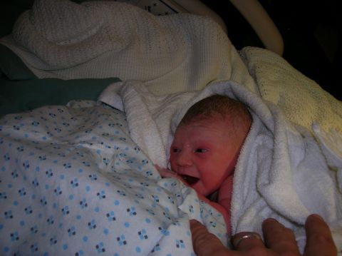 2003 Jeep TJ - A newborn baby is swaddled in a white towel, looking towards the camera.
