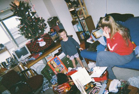 1990 Ford Bronco - Christmas morning in a living room: a young boy in a blue shirt and boxers stands among opened presents and toy boxes near a decorated tree…