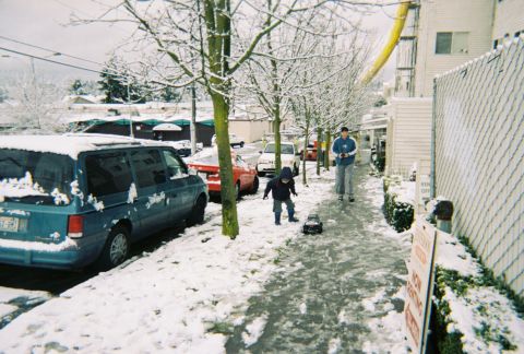 1990 Ford Bronco - A snowy day scene with children playing and vehicles parked along the street.